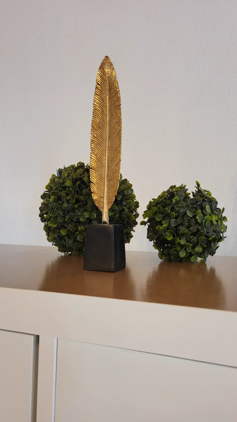 Dekoration mit goldener Feder und Buchsbaumkugeln